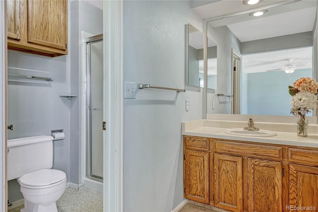 bathroom with vanity, toilet, ceiling fan, and a shower with shower door