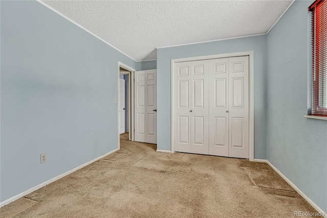 unfurnished bedroom with light colored carpet, a textured ceiling, and a closet