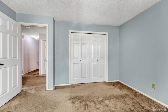 unfurnished bedroom with carpet, a textured ceiling, and a closet