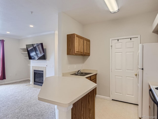 kitchen with kitchen peninsula, light colored carpet, sink, white refrigerator, and a fireplace