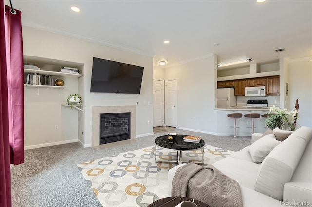 carpeted living room featuring a tile fireplace and ornamental molding