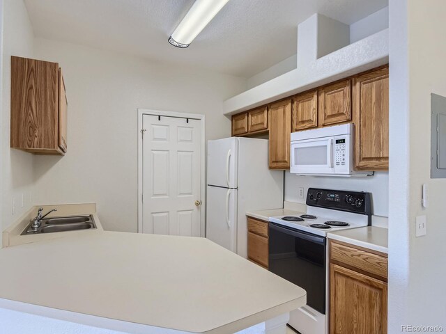 kitchen with a peninsula, white appliances, a sink, light countertops, and brown cabinets