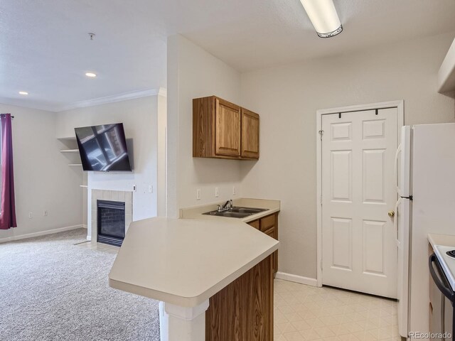 kitchen featuring light countertops, brown cabinetry, freestanding refrigerator, a sink, and a peninsula