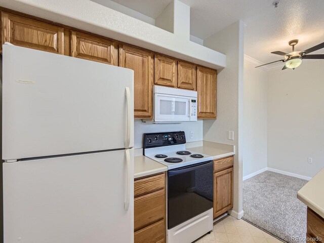 kitchen with brown cabinets, light countertops, a ceiling fan, white appliances, and baseboards