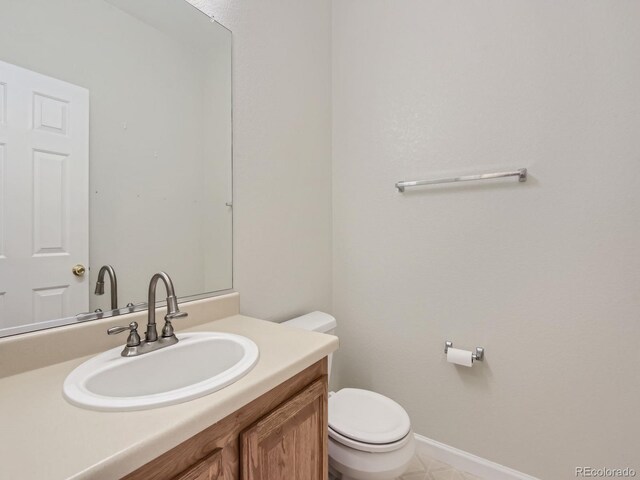 bathroom featuring toilet, baseboards, and vanity