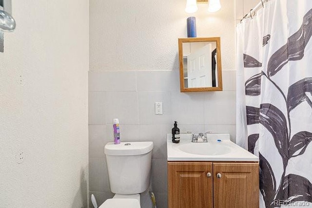 bathroom featuring a shower with curtain, vanity, toilet, and tile walls