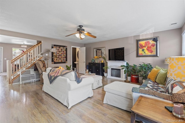 11062 Gaylord St, Northglenn, CO 80233 - living area featuring stairway, ceiling fan, wood finished floors, and a glass covered fireplace