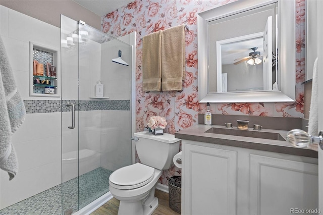 11062 Gaylord St, Northglenn, CO 80233 - full bathroom featuring wallpapered walls, vanity, a stall shower, ceiling fan, and wood finished floors