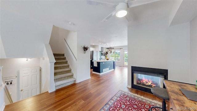 2560 Concord Cir, Lafayette, CO 80026 - living area featuring wood finished floors, stairway, a multi sided fireplace, and ceiling fan