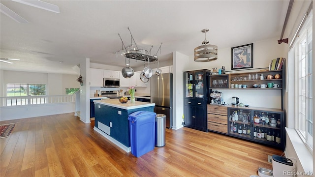 2560 Concord Cir, Lafayette, CO 80026 - kitchen with stainless steel appliances, light wood-style floors, white cabinets, light countertops, and a kitchen island