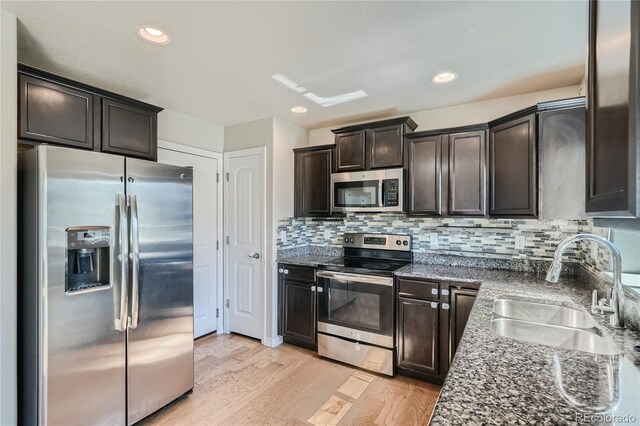 kitchen featuring dark brown cabinets, stainless steel appliances, light hardwood / wood-style floors, decorative backsplash, and sink