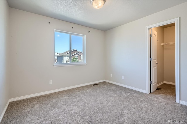 unfurnished bedroom with light carpet, a closet, and a walk in closet