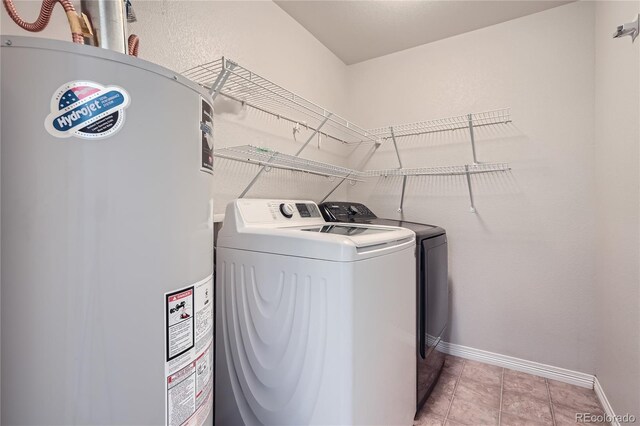 clothes washing area with washing machine and clothes dryer, gas water heater, and light tile patterned floors