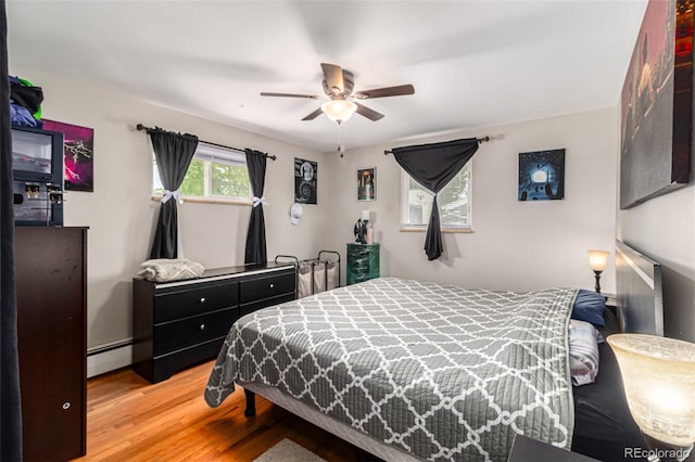 bedroom with ceiling fan, light hardwood / wood-style floors, and a baseboard radiator