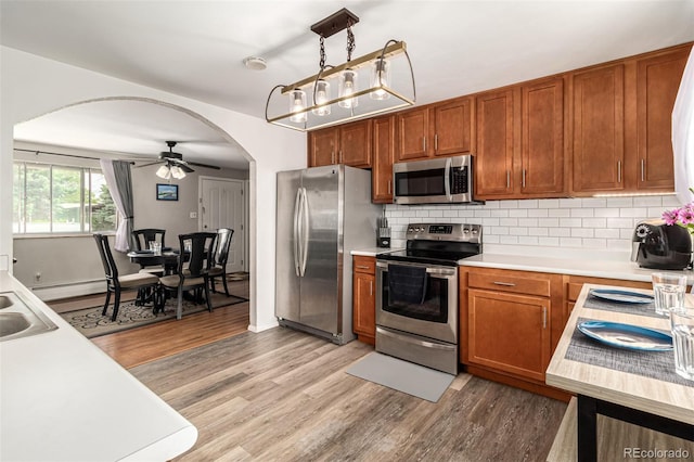 kitchen with ceiling fan, backsplash, pendant lighting, light hardwood / wood-style flooring, and stainless steel appliances