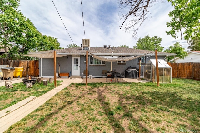 rear view of property with an outbuilding, an outdoor fire pit, a lawn, a patio area, and cooling unit