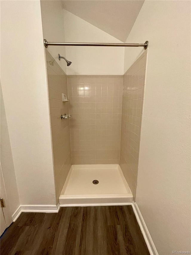 bathroom featuring vaulted ceiling, hardwood / wood-style floors, and a tile shower