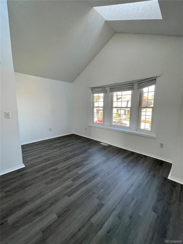 interior space featuring lofted ceiling with skylight, dark hardwood / wood-style floors, and a textured ceiling