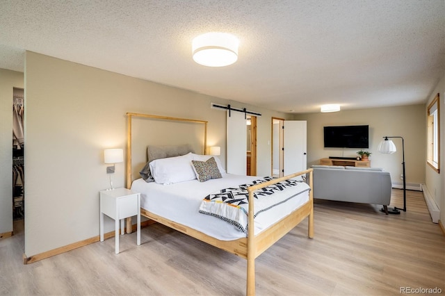 1194 Camp Eden Rd, Golden, CO 80403 - bedroom with light wood-style flooring, a textured ceiling, a barn door, a closet, and baseboards