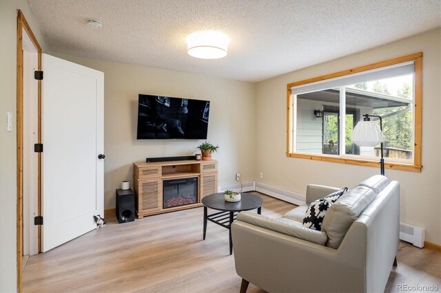 1194 Camp Eden Rd, Golden, CO 80403 - living room with light wood-style flooring, a baseboard radiator, a textured ceiling, and baseboards