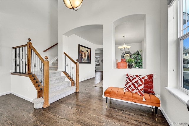 entryway with arched walkways, baseboards, a chandelier, and dark wood-type flooring