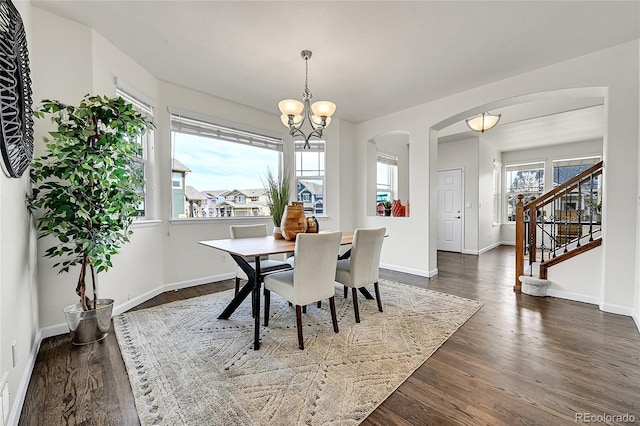 dining space with stairs, a notable chandelier, dark wood-style floors, baseboards, and arched walkways