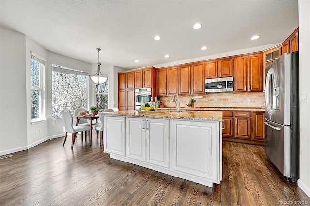 kitchen with dark wood-style flooring, brown cabinets, tasteful backsplash, and appliances with stainless steel finishes