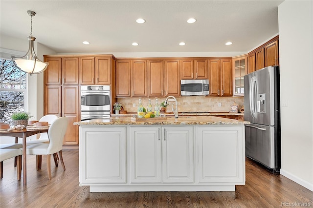 kitchen featuring decorative backsplash, stainless steel appliances, glass insert cabinets, and wood finished floors