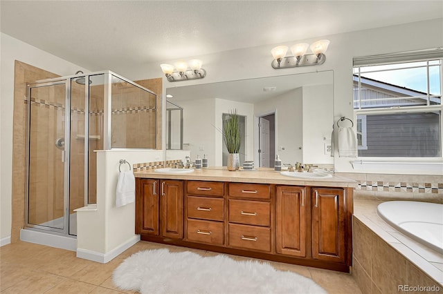 full bathroom with a relaxing tiled tub, double vanity, tile patterned floors, a sink, and a stall shower