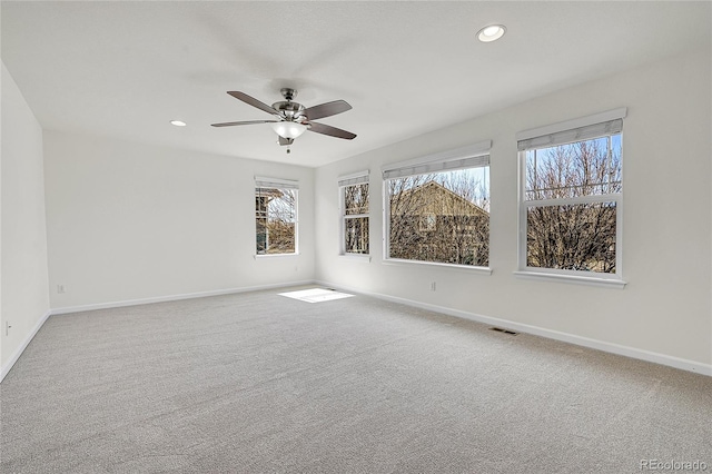 empty room featuring visible vents, baseboards, ceiling fan, and a wealth of natural light