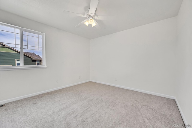 carpeted empty room with baseboards, visible vents, and a ceiling fan