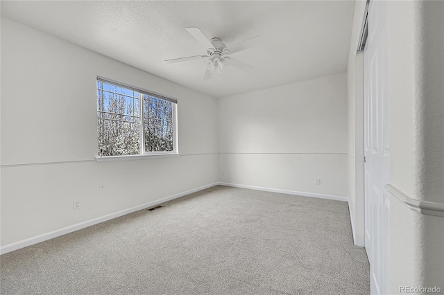 empty room featuring carpet flooring, a textured ceiling, baseboards, visible vents, and ceiling fan