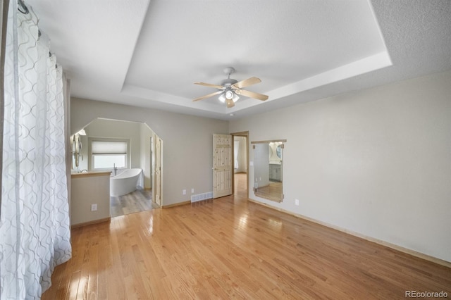 32501 E 137th Way, Brighton, CO 80603 - unfurnished bedroom with a tray ceiling, light wood-style flooring, connected bathroom, and baseboards