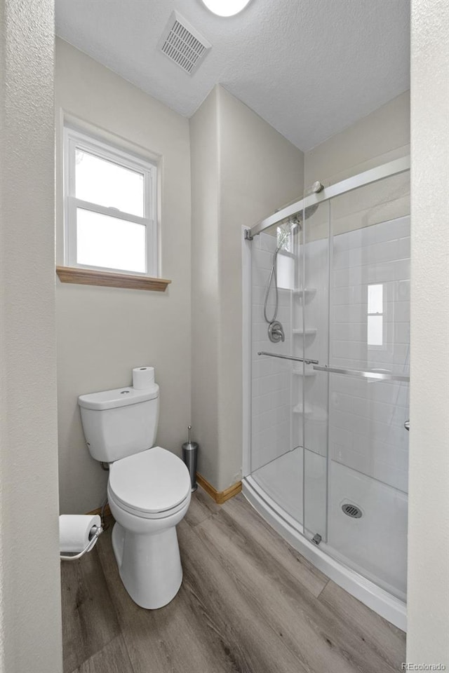 32501 E 137th Way, Brighton, CO 80603 - full bath with wood finished floors, toilet, a stall shower, a textured ceiling, and baseboards