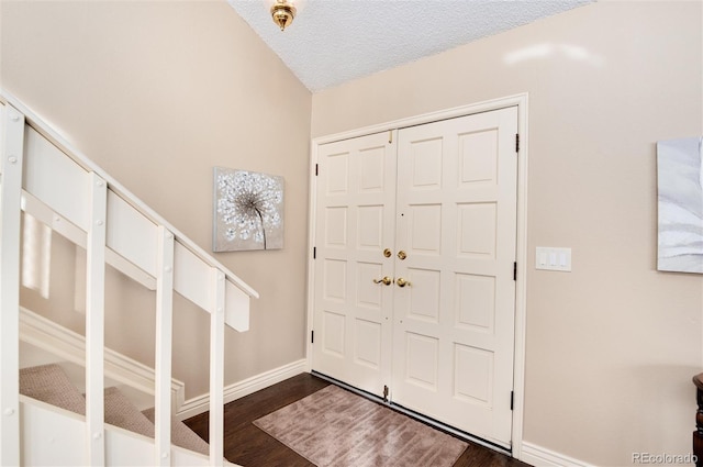 foyer entrance featuring a textured ceiling and dark wood-type flooring