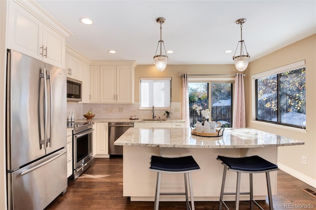 kitchen featuring appliances with stainless steel finishes, a kitchen island, pendant lighting, and sink