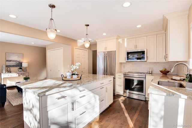 kitchen featuring stainless steel appliances, dark wood-type flooring, sink, decorative light fixtures, and a center island