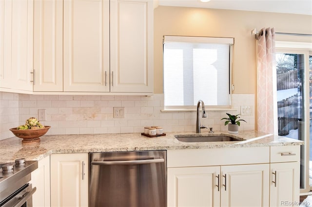 kitchen featuring dishwasher, white cabinets, sink, light stone countertops, and tasteful backsplash