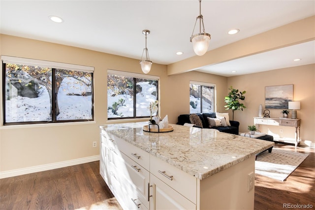 kitchen featuring light stone countertops, dark hardwood / wood-style flooring, pendant lighting, white cabinets, and a kitchen island