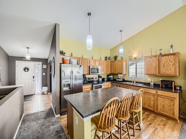 kitchen featuring vaulted ceiling, a center island, stainless steel appliances, and light hardwood / wood-style floors