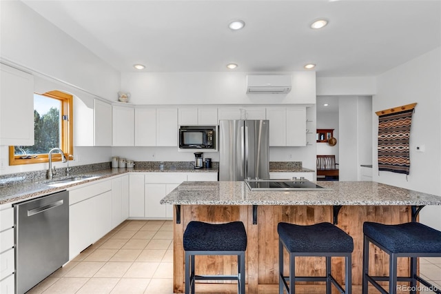 kitchen featuring white cabinetry, a center island, and black appliances