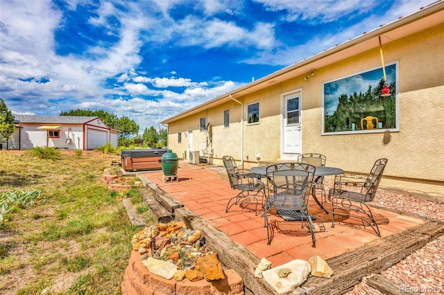 view of patio / terrace featuring central AC unit, an outbuilding, and a hot tub