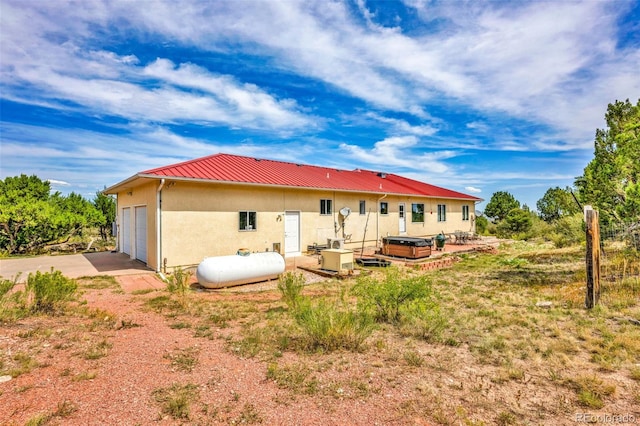 rear view of house with a hot tub and a garage