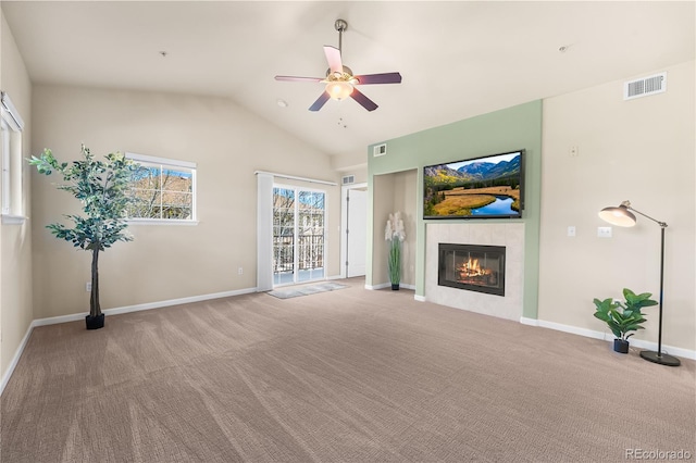 unfurnished living room featuring ceiling fan, a tiled fireplace, carpet floors, vaulted ceiling, and baseboards