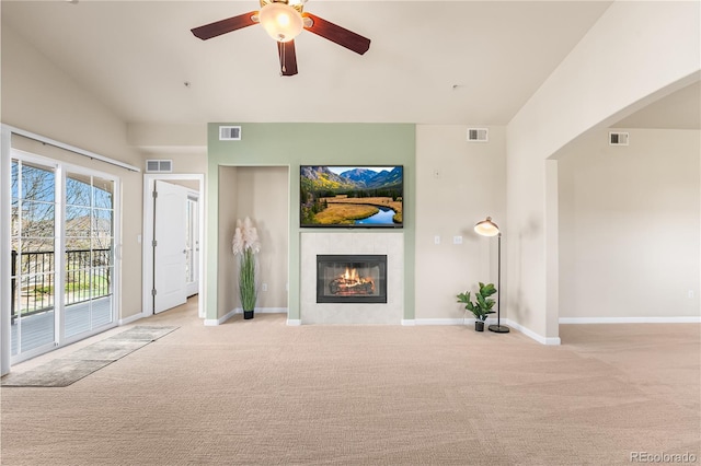 unfurnished living room featuring carpet flooring, a tiled fireplace, a ceiling fan, and baseboards
