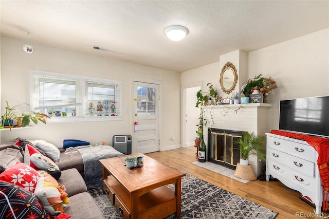 living room featuring a fireplace, a textured ceiling, and light wood-type flooring