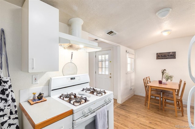 kitchen with lofted ceiling, light wood-type flooring, white gas range, a textured ceiling, and island exhaust hood