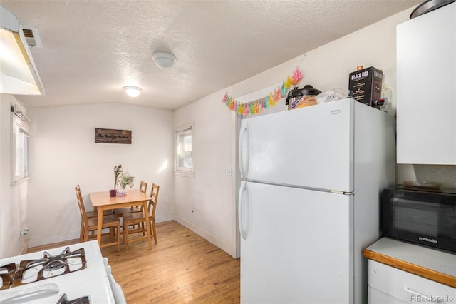 kitchen with a textured ceiling, white cabinetry, light hardwood / wood-style flooring, and white appliances