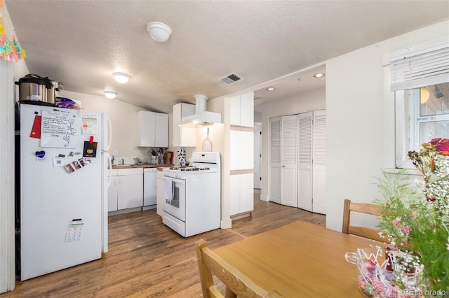 kitchen featuring white appliances, a textured ceiling, exhaust hood, wood-type flooring, and white cabinets