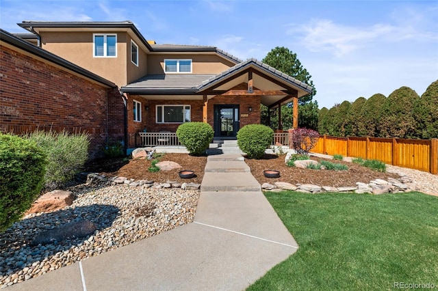 5925 Zinnia Ct, Arvada, CO 80004 - view of front facade with covered porch, a tile roof, brick siding, and stucco siding